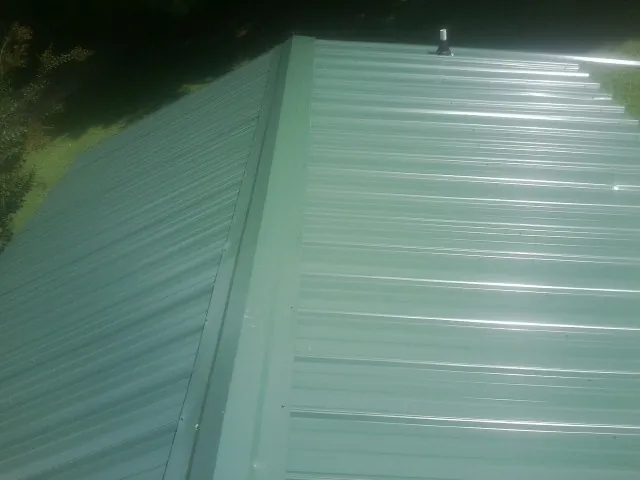 New green metal panels meeting at the ridge of a roof — Flat Roof Repair work by our crew in Bivalve