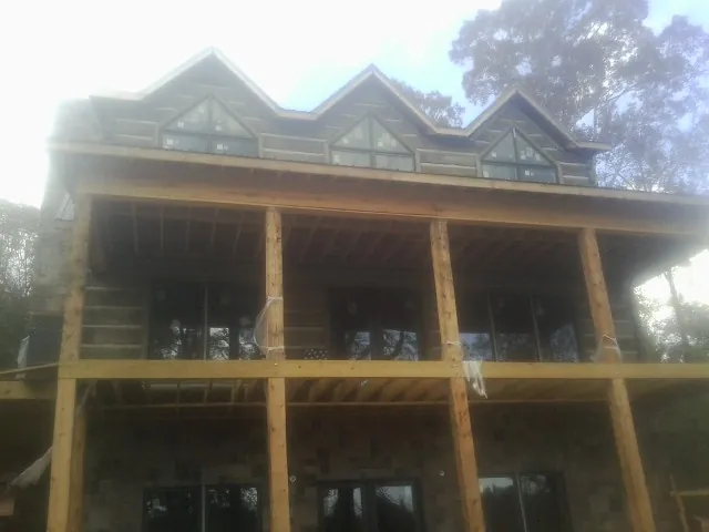 Dormers and porch framing on a large log home under construction — Roof Coating work by our crew in Bivalve