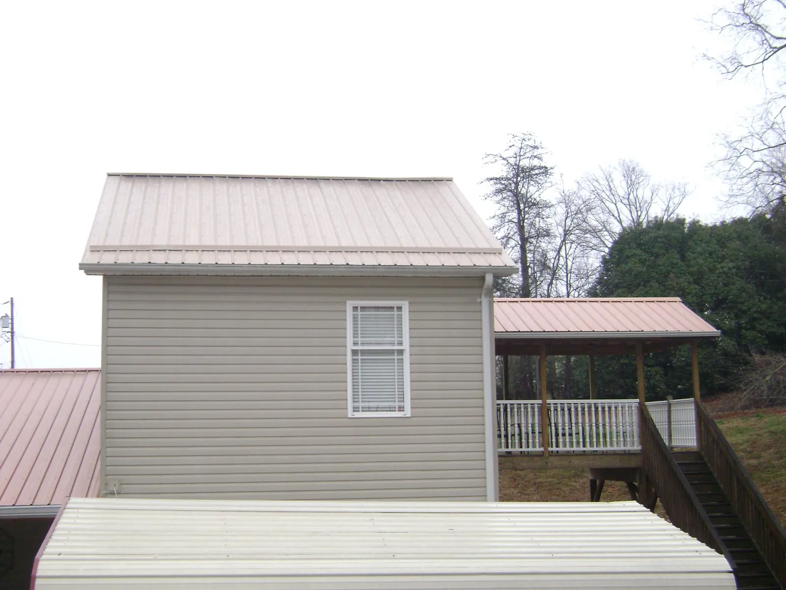 Tan metal roofs on a two story addition and attached porch, from a Roof Replacement job in Bivalve
